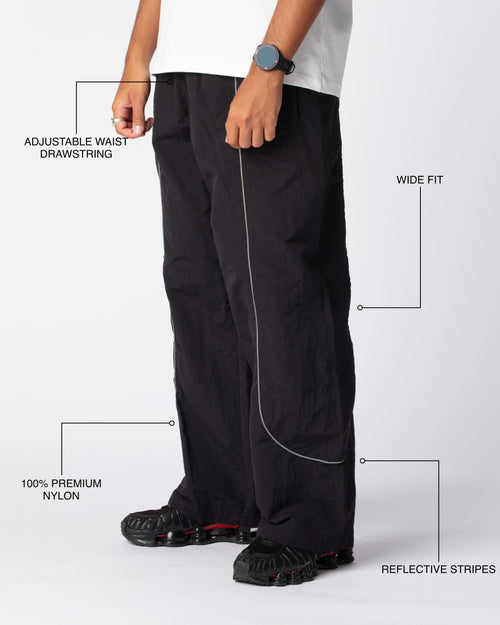 Diagonal Track Pants Obsidian shot, showing adjustable waist drawstring, wide fit, premium nylon material and signature curved reflective stripes
