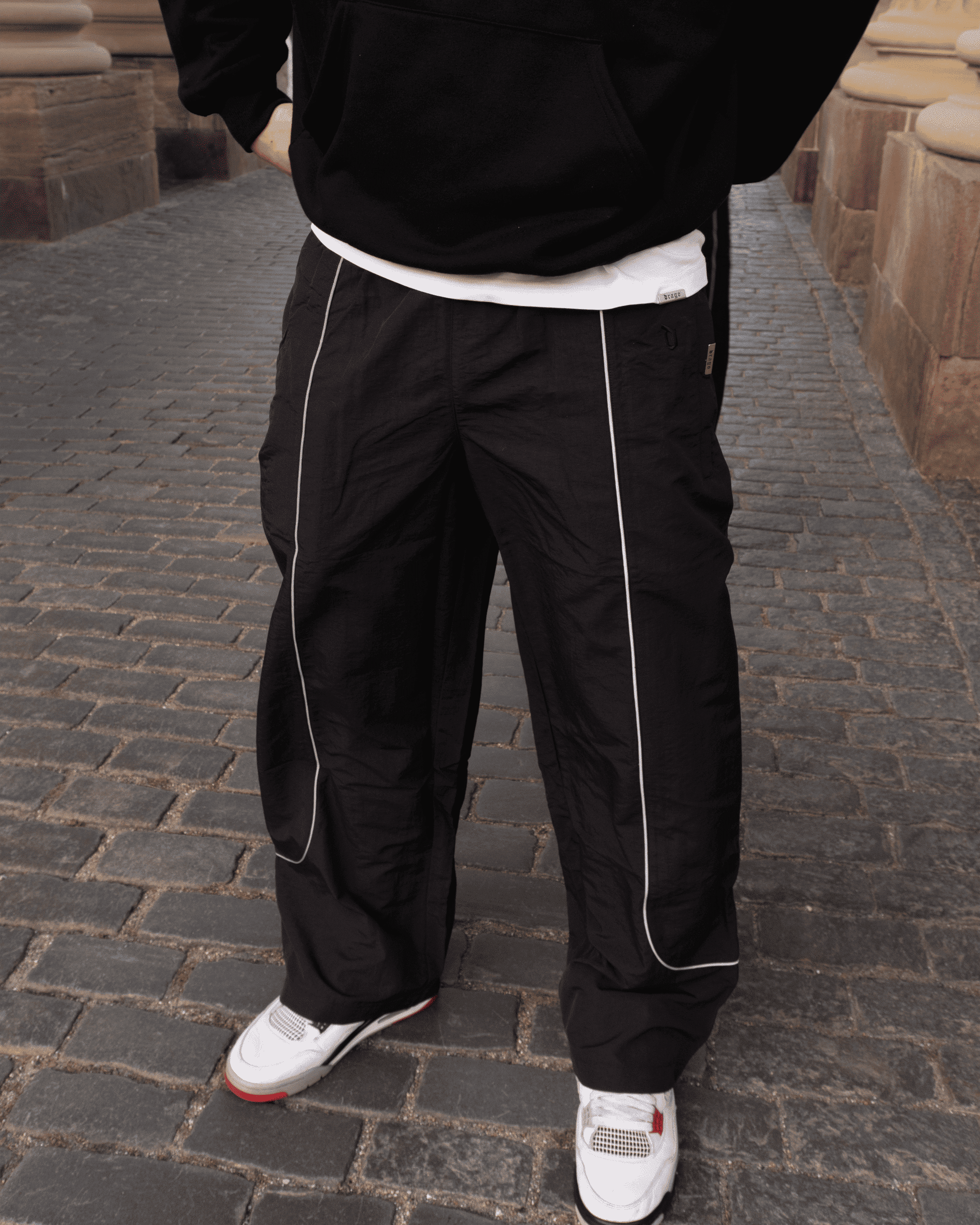 Mathias in our Track Pants Obsidian in a classic setting with stone flooring