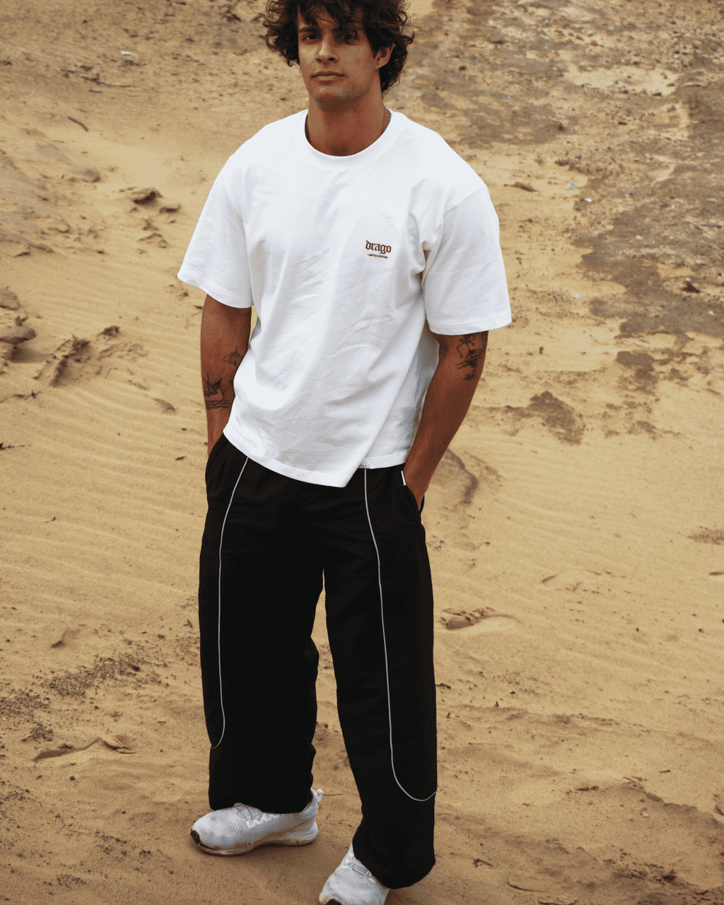 Daniel in an exotic dune setting wearing our Track Pants Obsidian