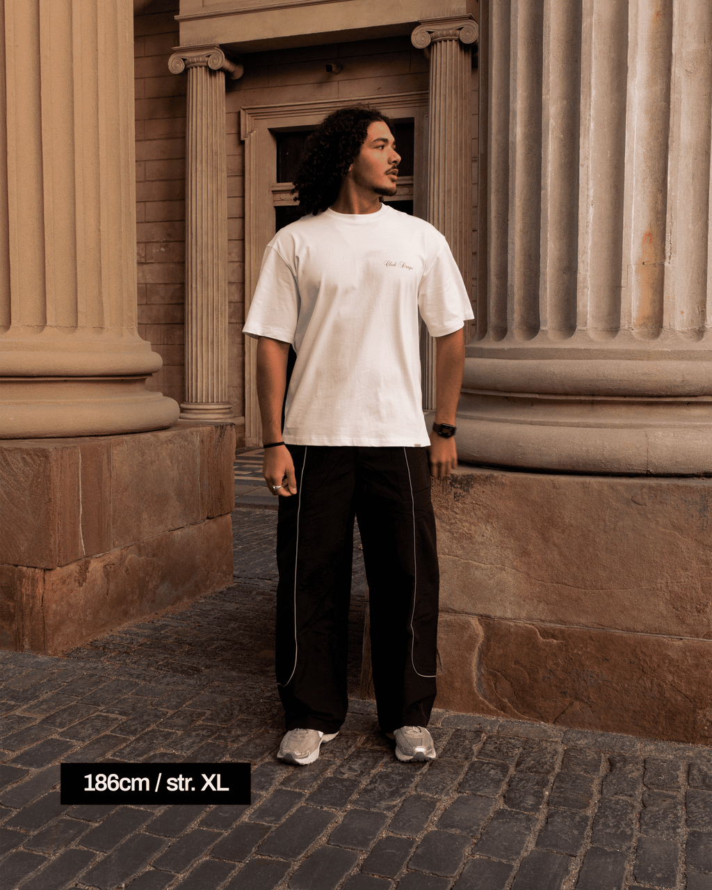 Ahmed in a classical setting, with Stone pillars wearing our Track Pants Obsidian