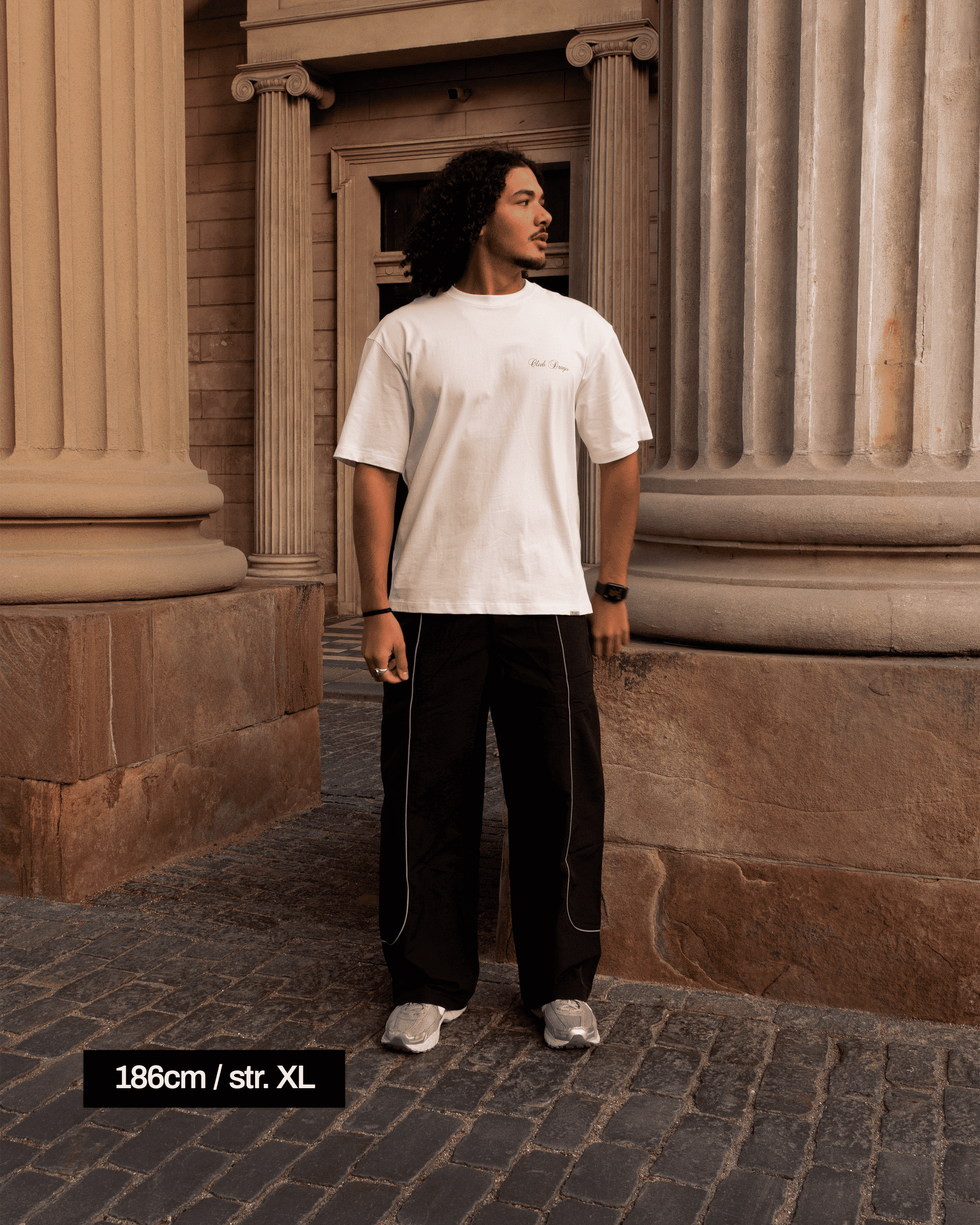 Ahmed in a classical setting, with Stone pillars wearing our Track Pants Obsidian