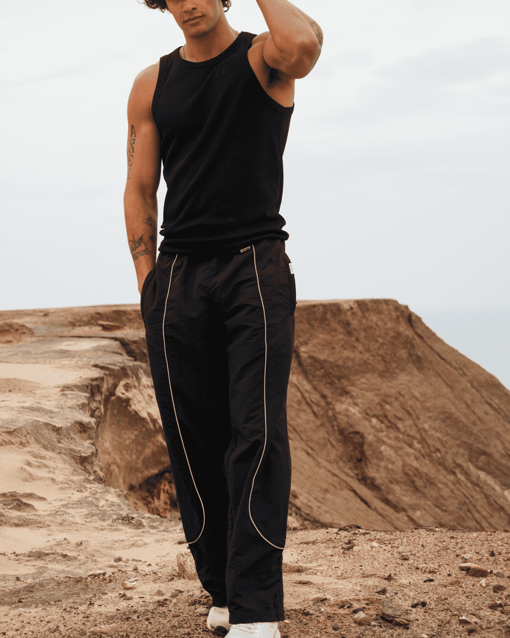 Daniel Comparino in our Track Pants Obsidian in a nature setting on a sand dune hill