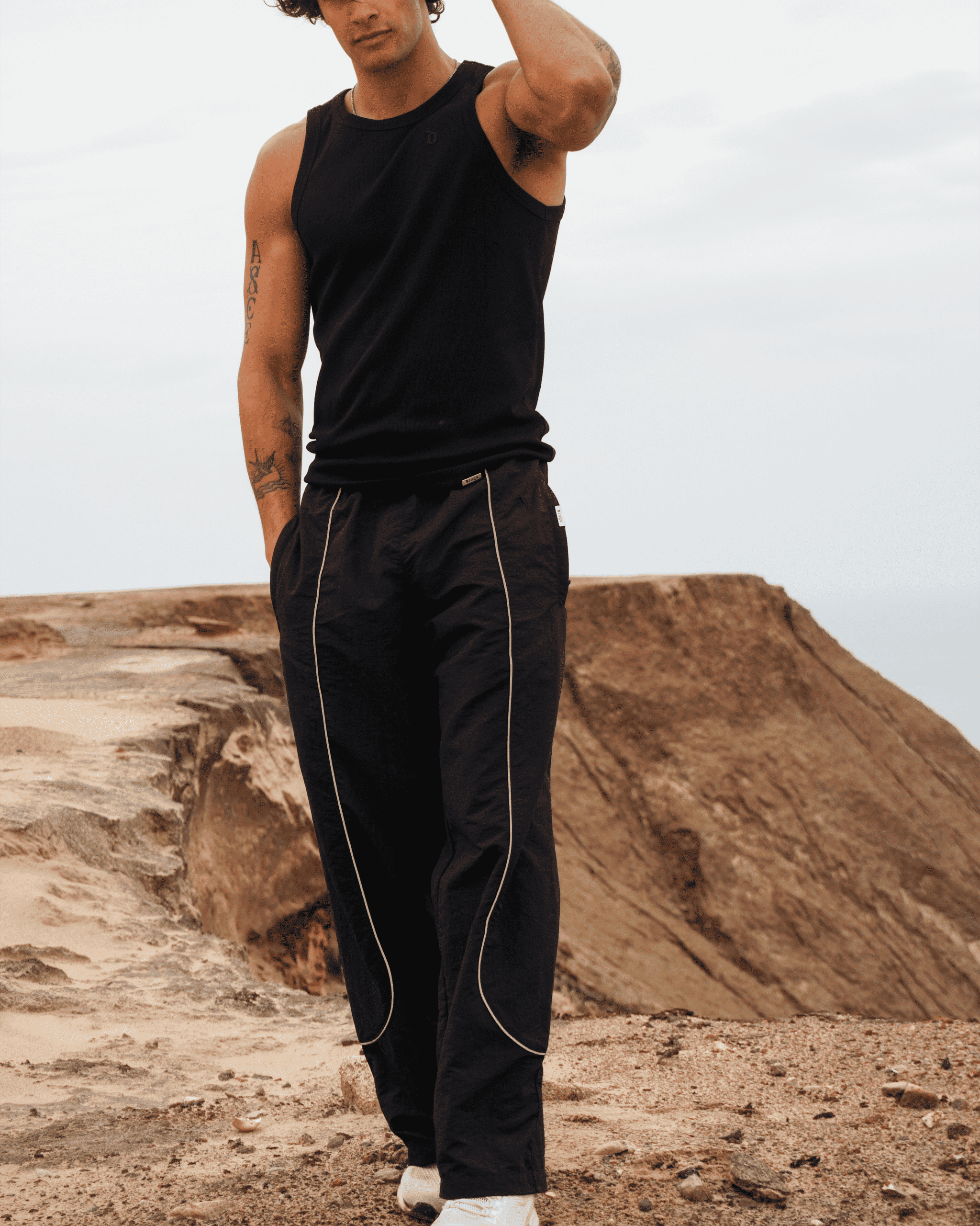 Daniel Comparino in our Track Pants Obsidian in a nature setting on a sand dune hill